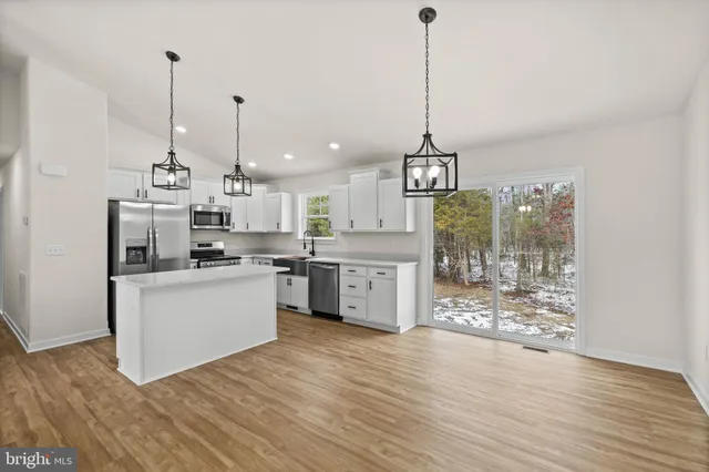 a kitchen with kitchen island granite countertop a stove a sink a center island a refrigerator and a wooden floor