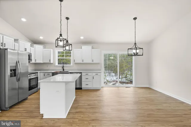 a kitchen with stainless steel appliances granite countertop a sink a stove a refrigerator and island with wooden floor