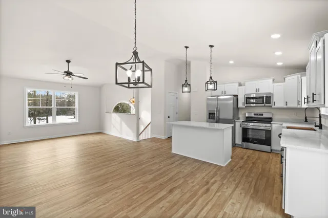 a kitchen with stainless steel appliances granite countertop a stove top oven a sink dishwasher and a wooden floor