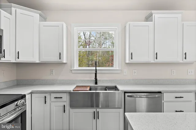 a kitchen with stainless steel appliances granite countertop white cabinets and a window