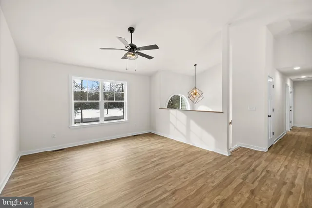 a view of empty room with wooden floor and fan