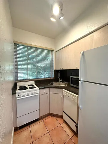 a kitchen with a stove a sink and white stainless steel appliances
