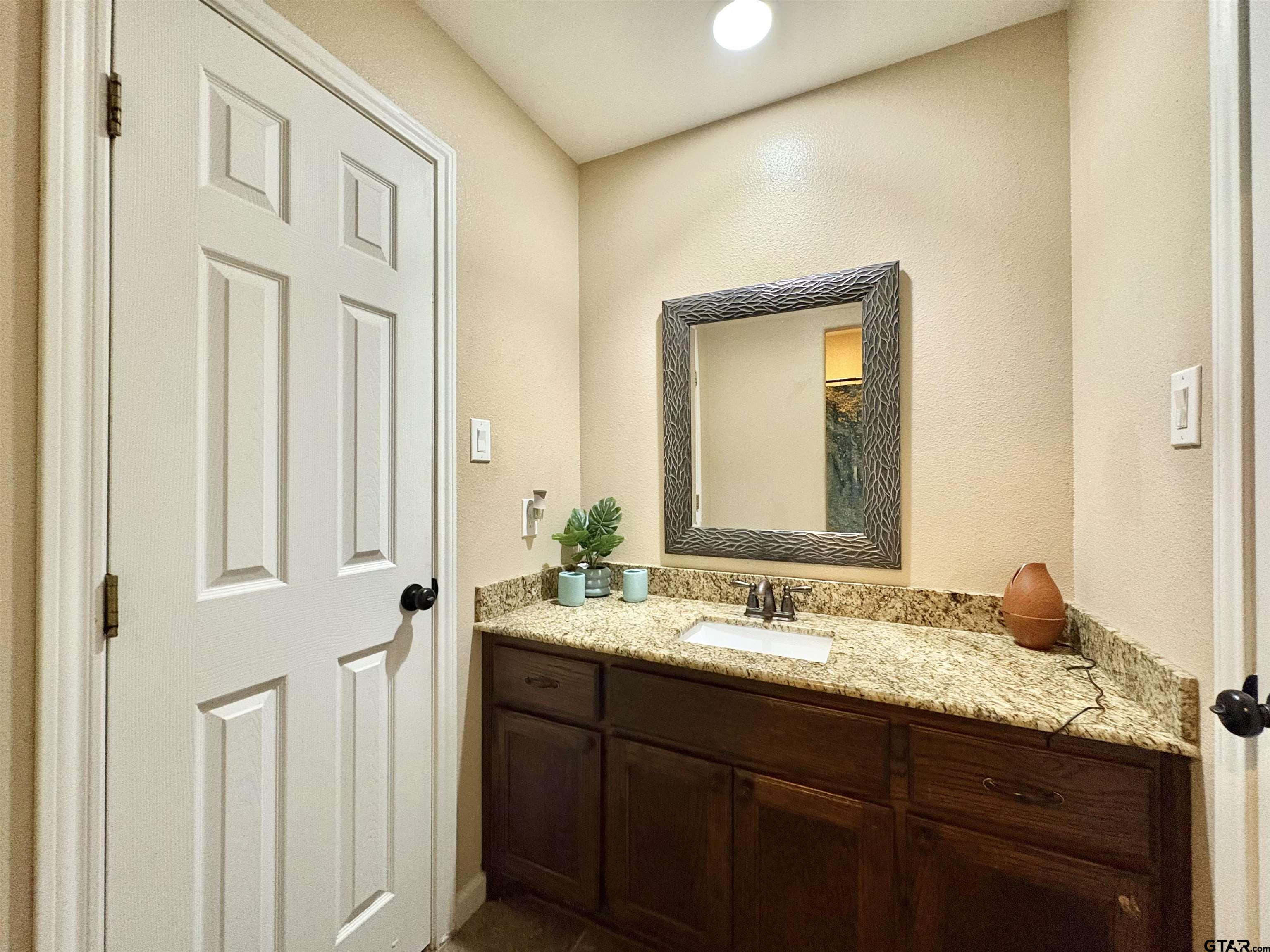 28 County Road 3101 Pittsburg, TX 75686 - Photo 26 of 39 a bathroom with a granite countertop sink and a mirror