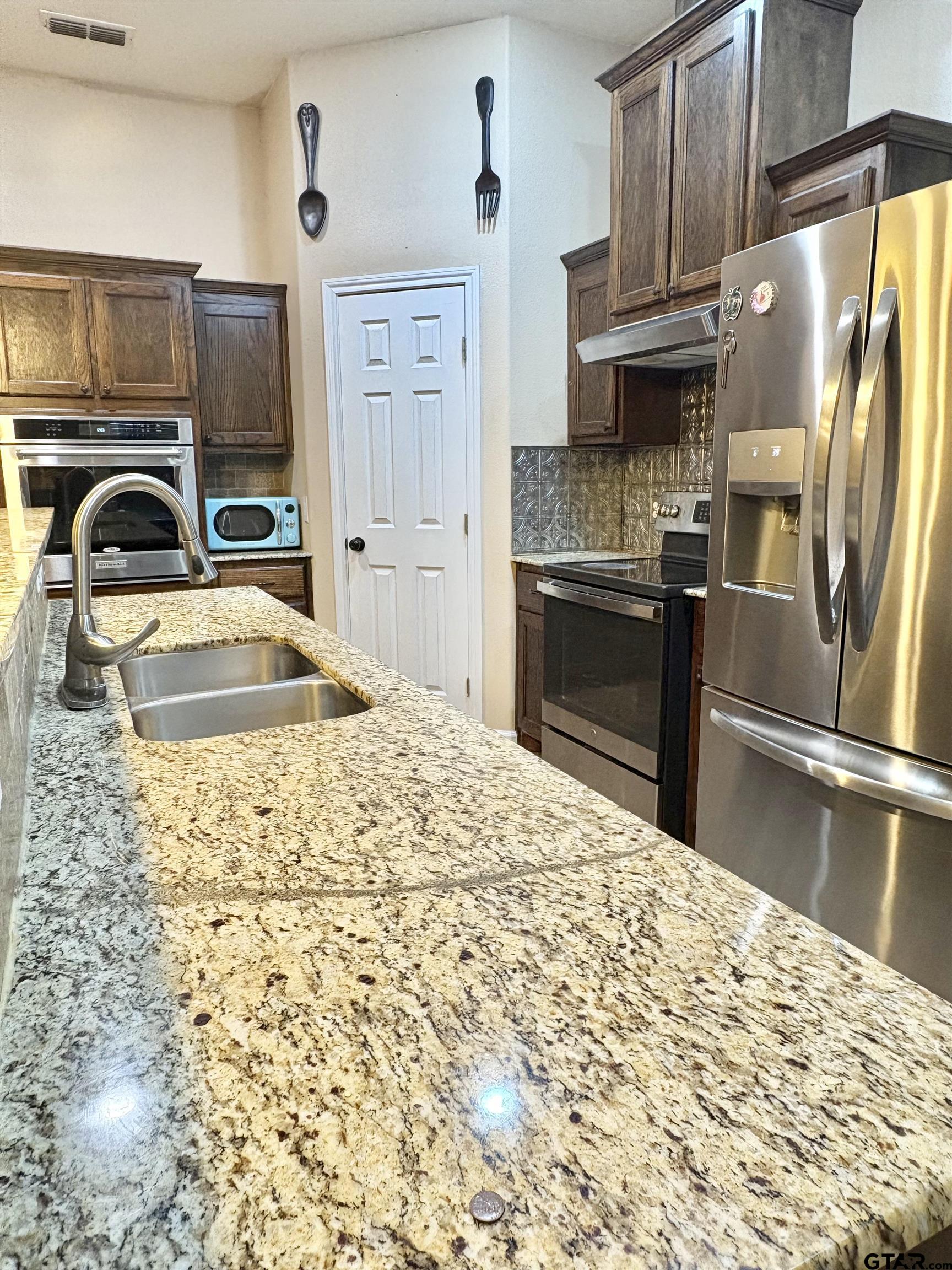 28 County Road 3101 Pittsburg, TX 75686 - Photo 9 of 39 a kitchen with granite countertop a refrigerator and a stove top oven