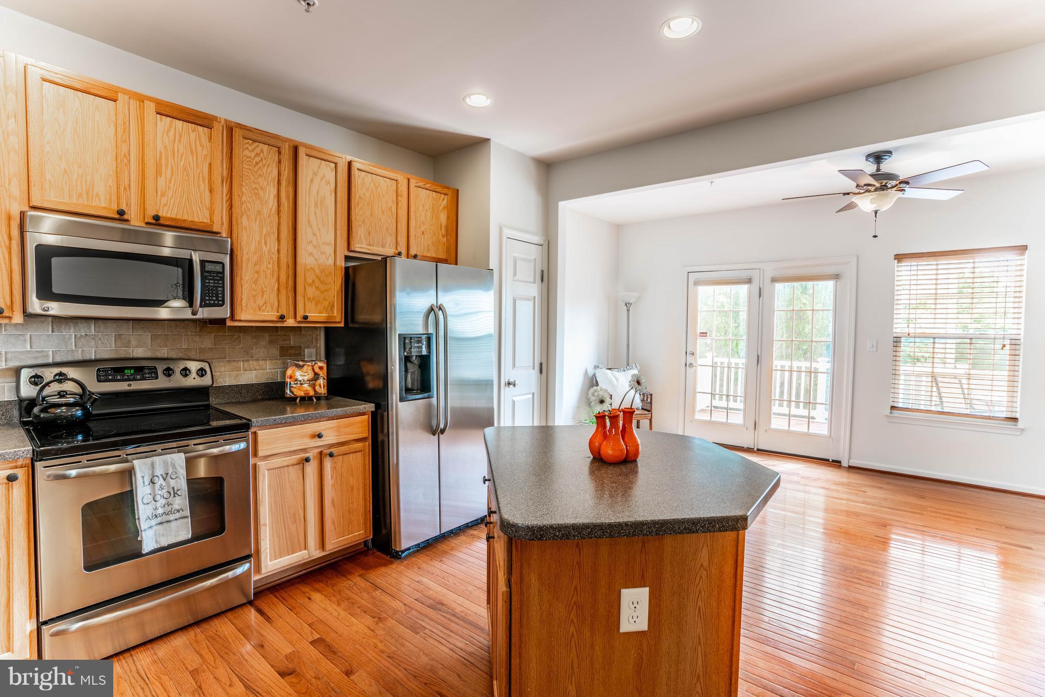 6876 Tasker Falls, Unit 77 Elkridge, MD 21075 - Photo 2 of 30 a kitchen with stainless steel appliances a stove top oven a sink dishwasher a refrigerator and a dining table with wooden floor