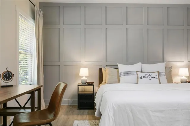 a bedroom with a bed a chair and potted plant on the dresser