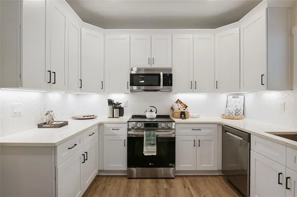 a kitchen with stainless steel appliances granite countertop white cabinets sink and stove