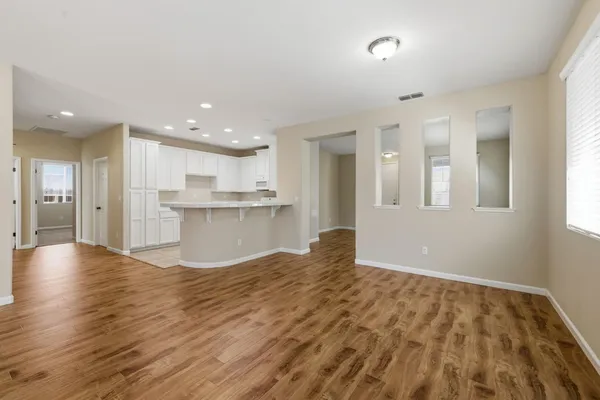 a view of empty room with kitchen and window