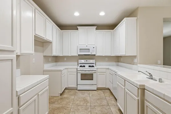 a kitchen with white cabinets sink and white appliances