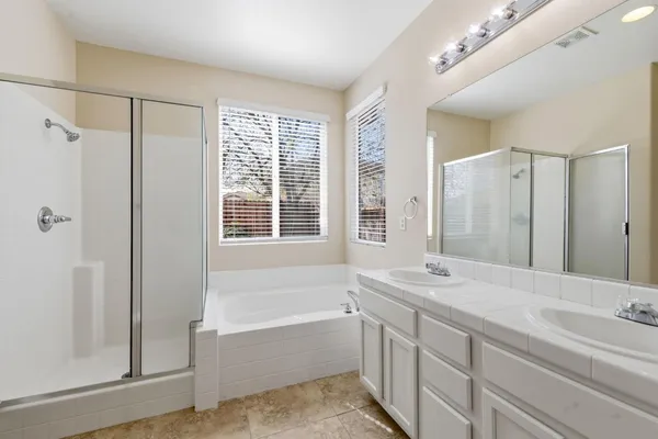 a bathroom with a granite countertop tub sink and mirror