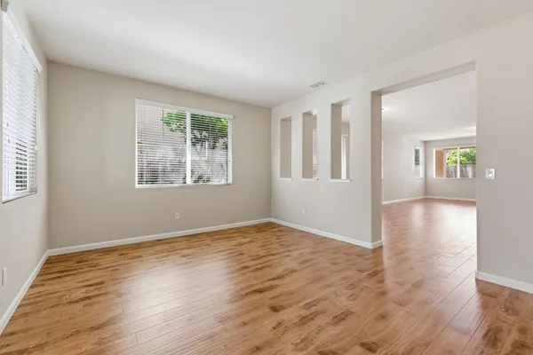a view of an empty room with wooden floor and a window