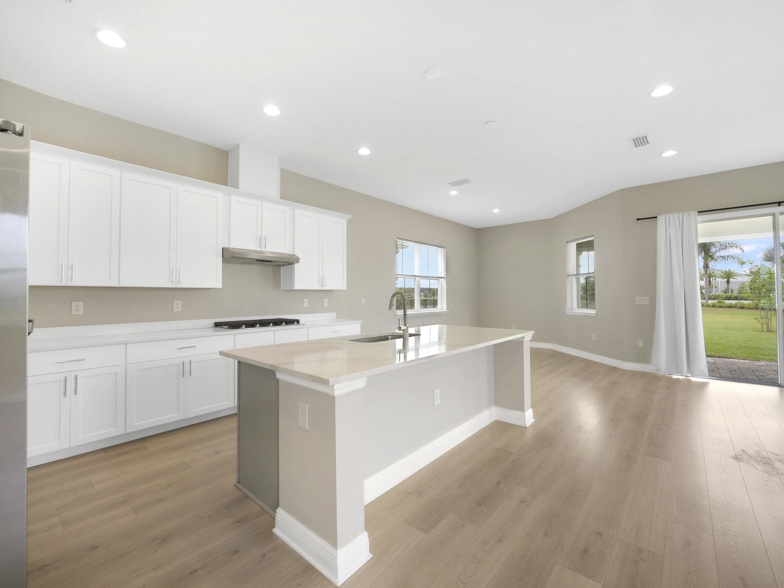 471 Rum Runner Way St. Johns, FL 32259 - Photo 11 of 42 a large white kitchen with kitchen island a sink a stove a refrigerator and white cabinets with wooden floor