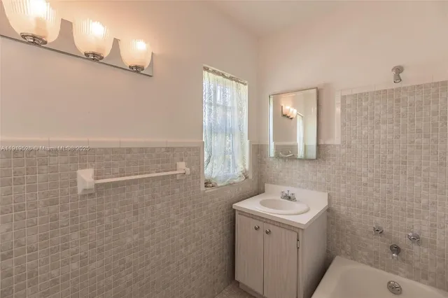a spacious bathroom with a tub sink and mirror