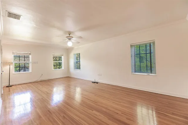 a view of empty room with wooden floor and fan
