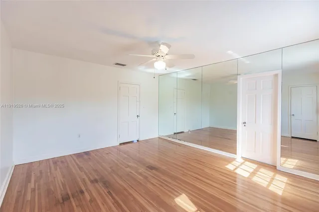 a view of a big room with wooden floor and windows