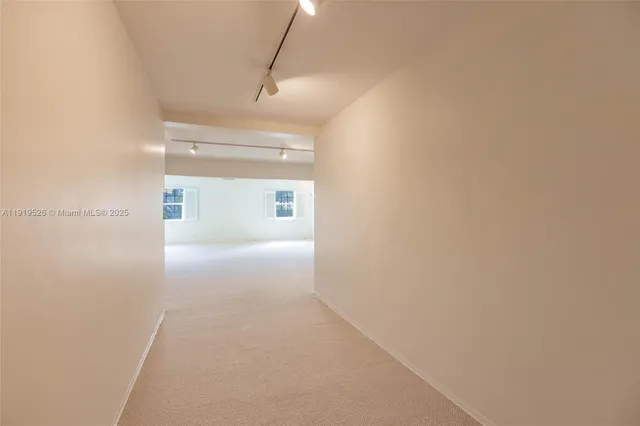 a view of an empty room with wooden floor and a kitchen