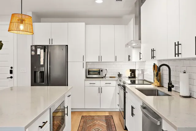 a kitchen with stainless steel appliances a sink a stove a refrigerator and cabinets