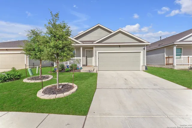 a view of a white house with a small yard and potted plants