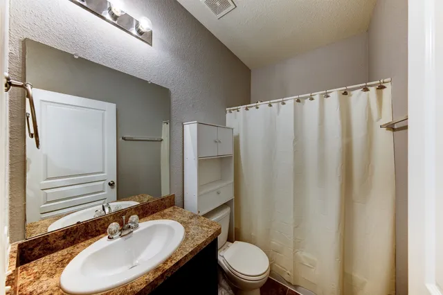 a bathroom with a granite countertop sink toilet and shower