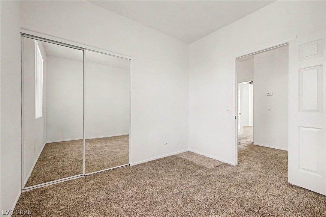 2223 Ramsgate Drive Henderson, NV 89074 - Photo 19 of 32 A spacious bedroom features plush carpeting and mirrored closet doors, creating an open and airy feel.