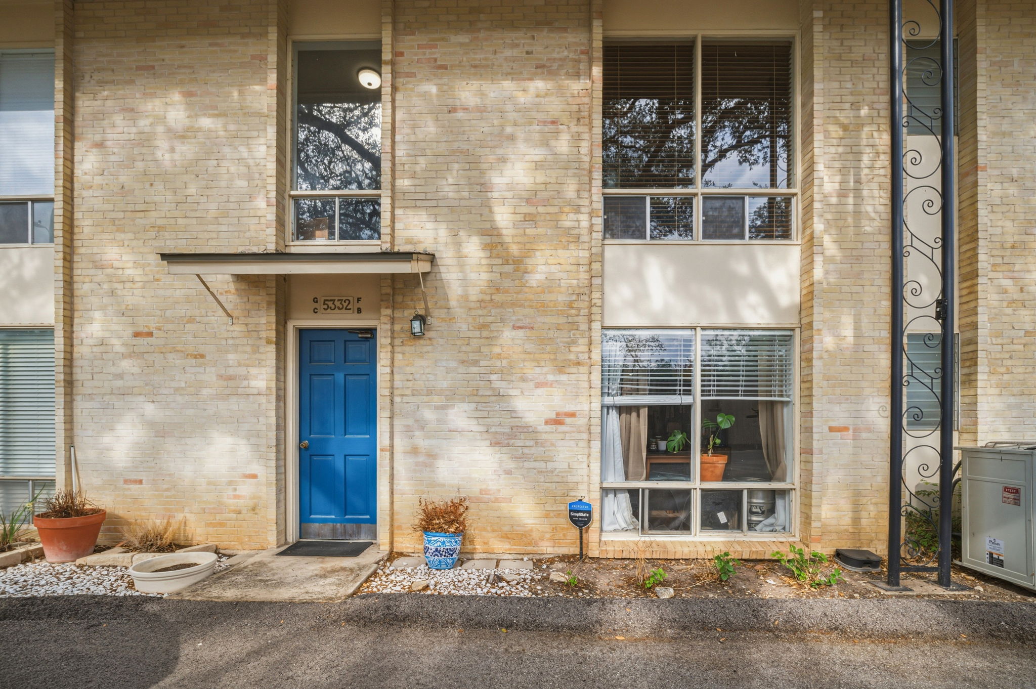 5332 Balcones Drive, Unit B Austin, TX 78731 - Photo 2 of 15 The property features a light-colored brick exterior with a vibrant blue entrance door, covered by a small overhang