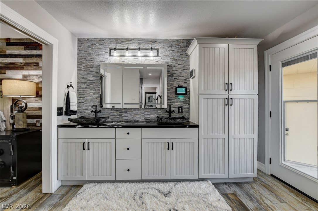 6460 Racel Street Las Vegas, NV 89131 - Photo 44 of 59 Double vanity sinks and built-in cabinetry anchor this modern bathroom space with textured accents.