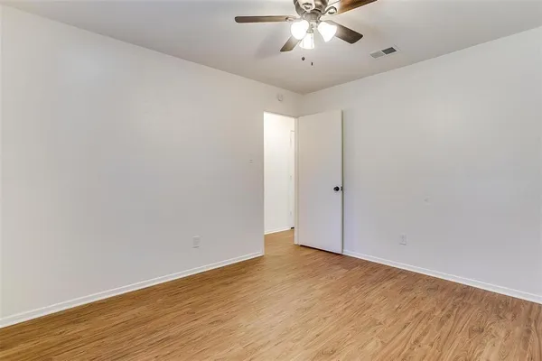 an empty room with wooden floor and fan