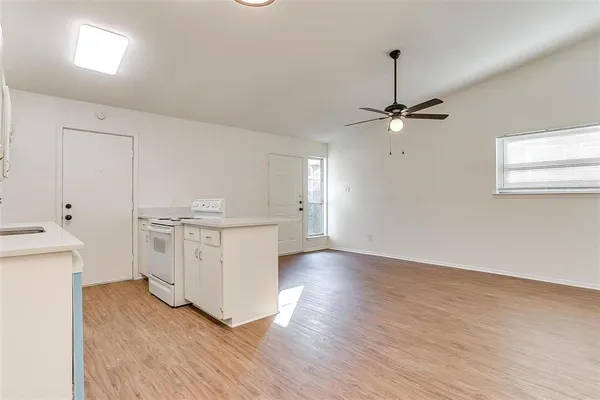 a view of an empty room with a window and wooden floor