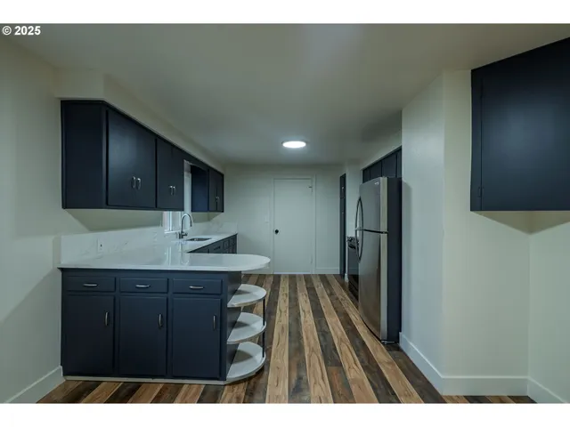 a kitchen with a sink a refrigerator and wooden cabinets