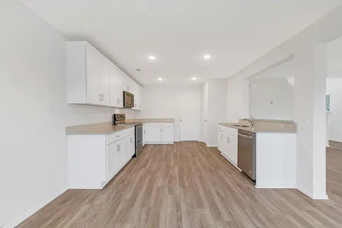 a large kitchen with a white wooden cabinets and wooden floor