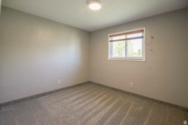 634 South 2100th Street West Vernal, UT 84078 - Photo 31 of 71 Room featuring light gray walls, gray carpet, a white framed window with brown blinds, and a flush mount ceiling light