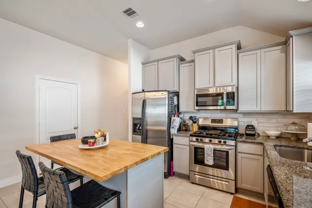 a kitchen with stainless steel appliances kitchen island a table chairs sink and stove