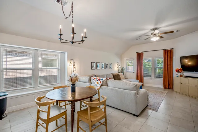 a living room with fireplace a flat screen tv and a chandelier