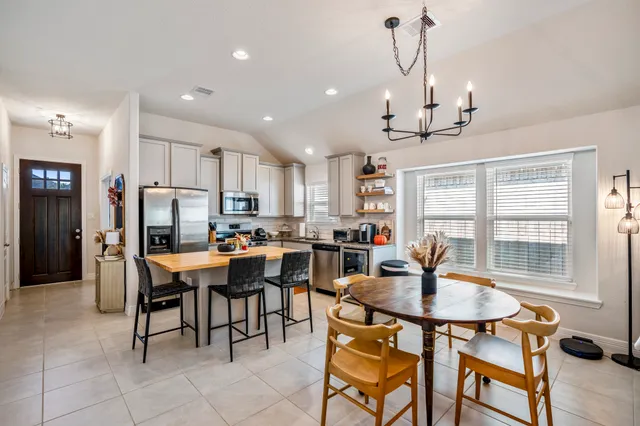 a dining room with stainless steel appliances kitchen island granite countertop a dining table chairs and granite counter tops