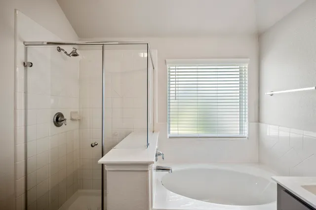 a bathroom with a bathtub a shower and a window