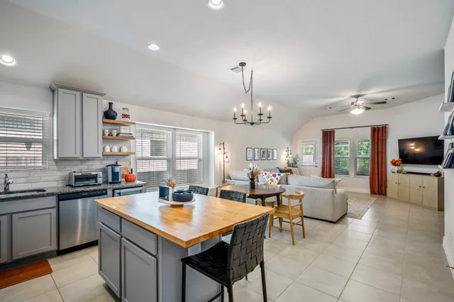 a kitchen with a stove a sink a counter top space and living room view