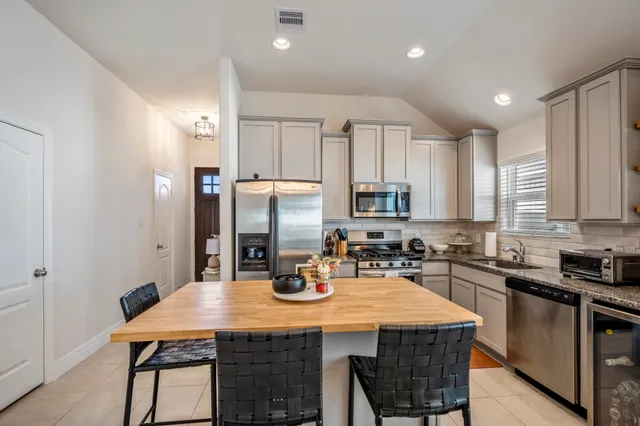 a kitchen with stainless steel appliances granite countertop a kitchen island a stove a sink a dining table and chairs