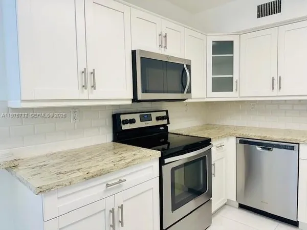 a kitchen with granite countertop white cabinets stainless steel appliances and a sink