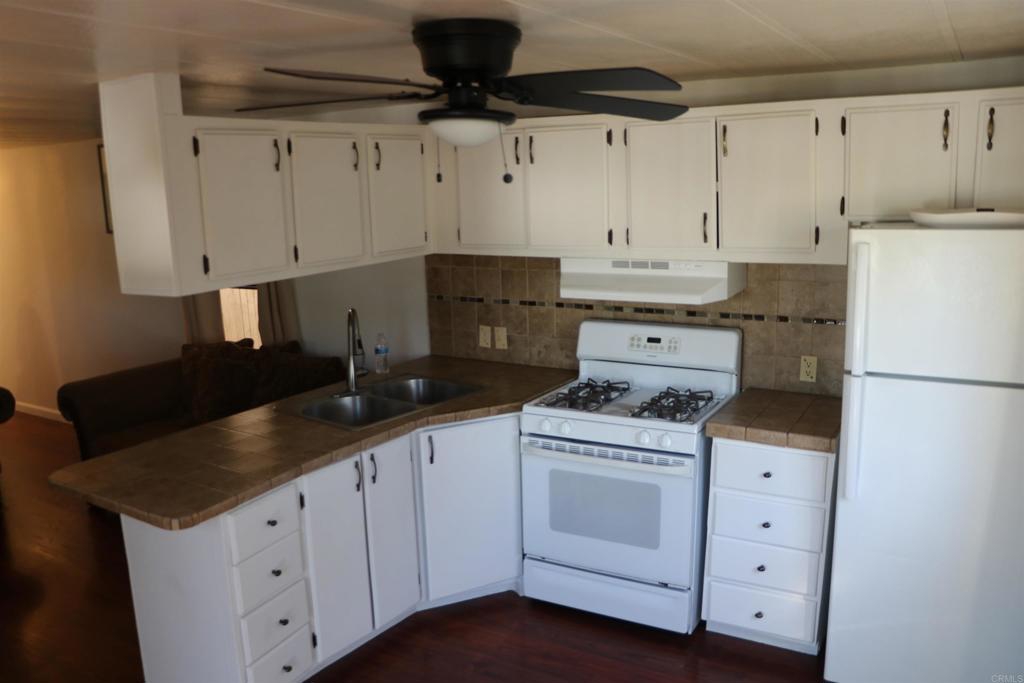 1455 Alturas Road, Unit 89 Fallbrook, CA 92028 - Photo 4 of 14 a kitchen with granite countertop white cabinets and white appliances