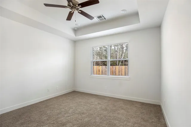 an empty room with ceiling fan and window