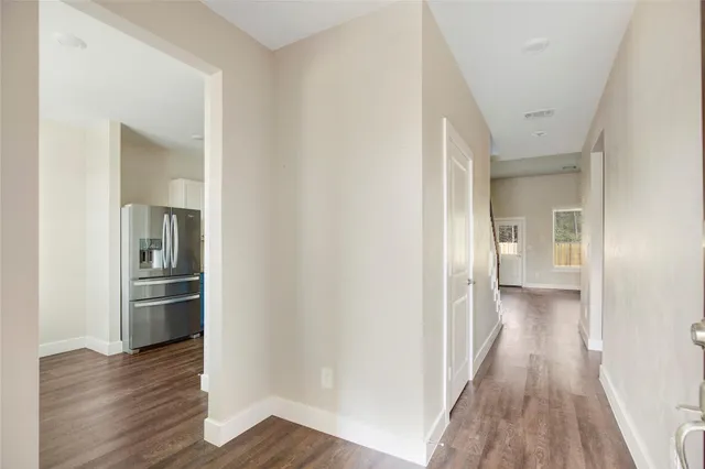 a view of a hallway with wooden floor and a kitchen