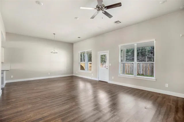 a view of an empty room with a window and wooden floor