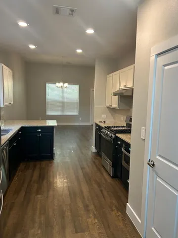 a kitchen with granite countertop a refrigerator and a stove top oven