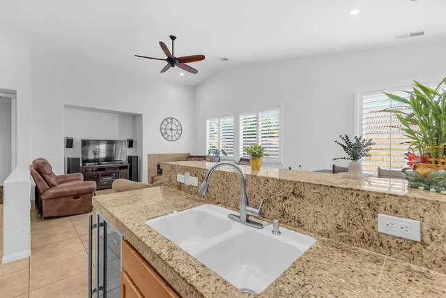 a living room with granite countertop furniture a sink a flat screen tv and a large window