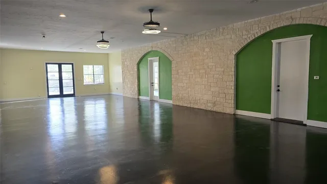 an empty room with wooden floor chandelier and windows