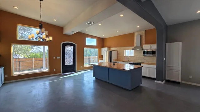 a dining hall with stainless steel appliances granite countertop a refrigerator a sink dishwasher and a flat tv screen next to a window