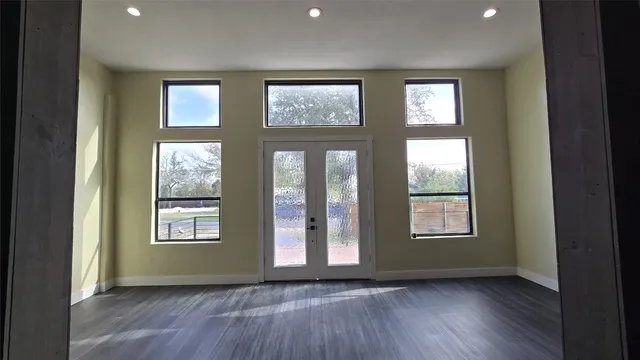an empty room with wooden floor and windows