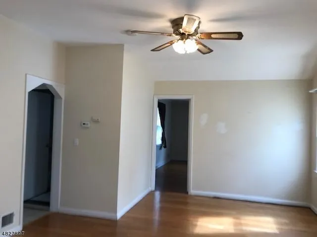 an empty room with wooden floor closet and fan