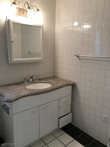 a bathroom with a granite countertop sink a mirror and a shower