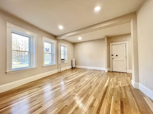 a view of an empty room and window and wooden floor